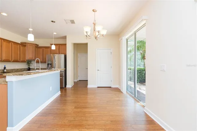 a large kitchen with kitchen island a island a stove a refrigerator a sink dishwasher a oven with white cabinets and wooden floor