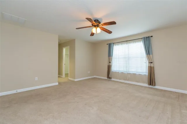 an empty room with windows and fan