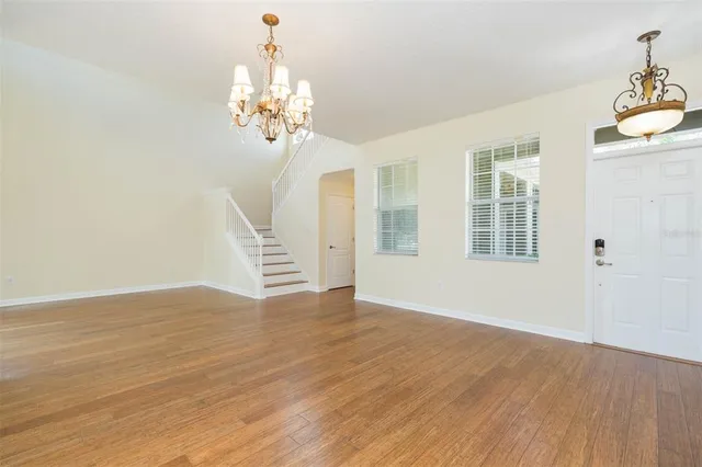 a view of an empty room with wooden floor and a chandelier