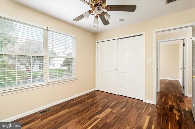 a view of empty room with wooden floor and fan