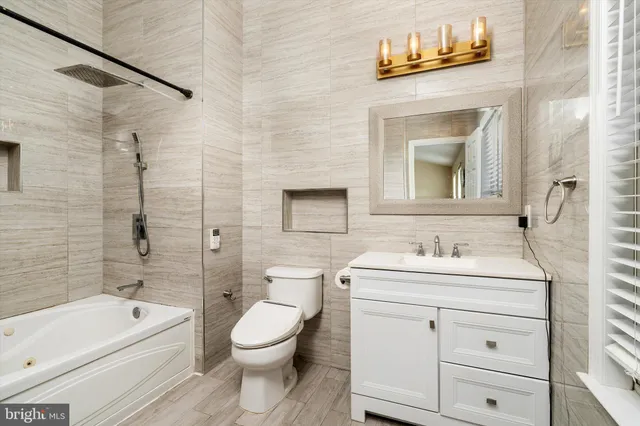 a bathroom with a toilet sink vanity tub and shower