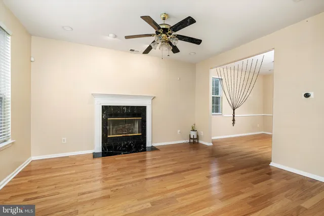 an empty room with wooden floor fan and windows