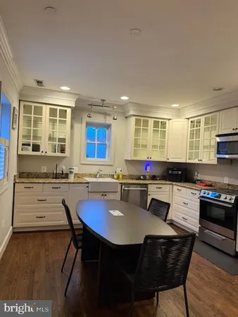 a kitchen with stainless steel appliances granite countertop a stove a sink dishwasher a dining table and chairs with wooden floor