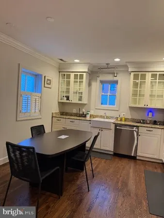 a kitchen with a dining table chairs and wooden floor