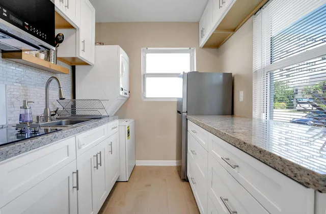 a kitchen with stainless steel appliances granite countertop a sink and a refrigerator