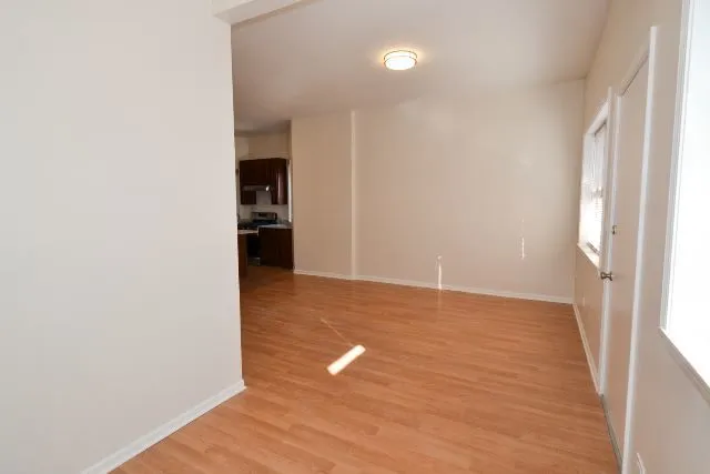 a view of empty room with wooden floor and fan