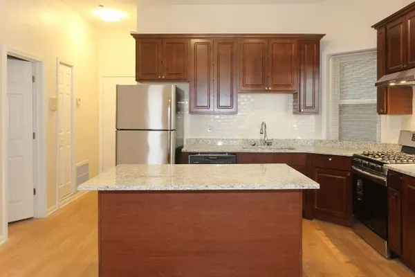 a kitchen with kitchen island granite countertop a sink stove and refrigerator