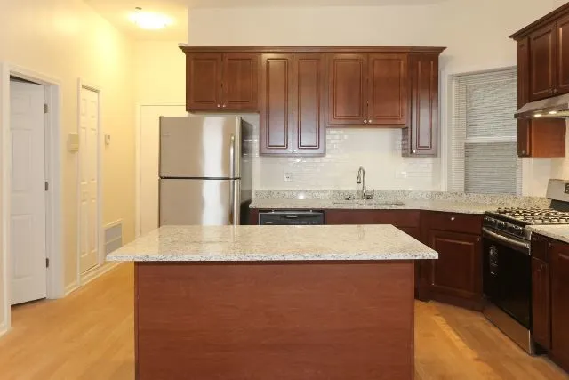 a kitchen with kitchen island granite countertop a sink stove and refrigerator