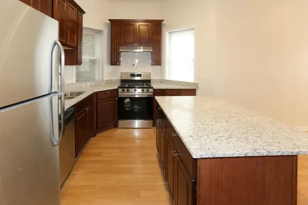 a kitchen with stainless steel appliances granite countertop a refrigerator a stove and a sink with wooden floor