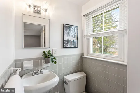 a bathroom with a toilet a sink a mirror a window and vanity