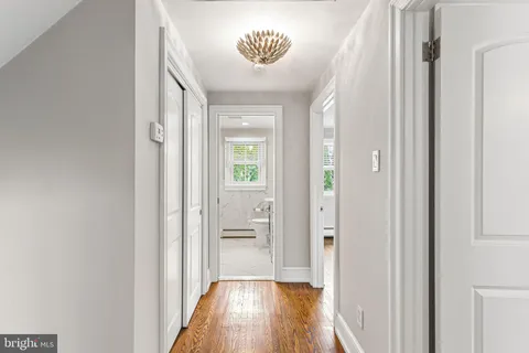 a view of a hallway with wooden floor and a bathroom