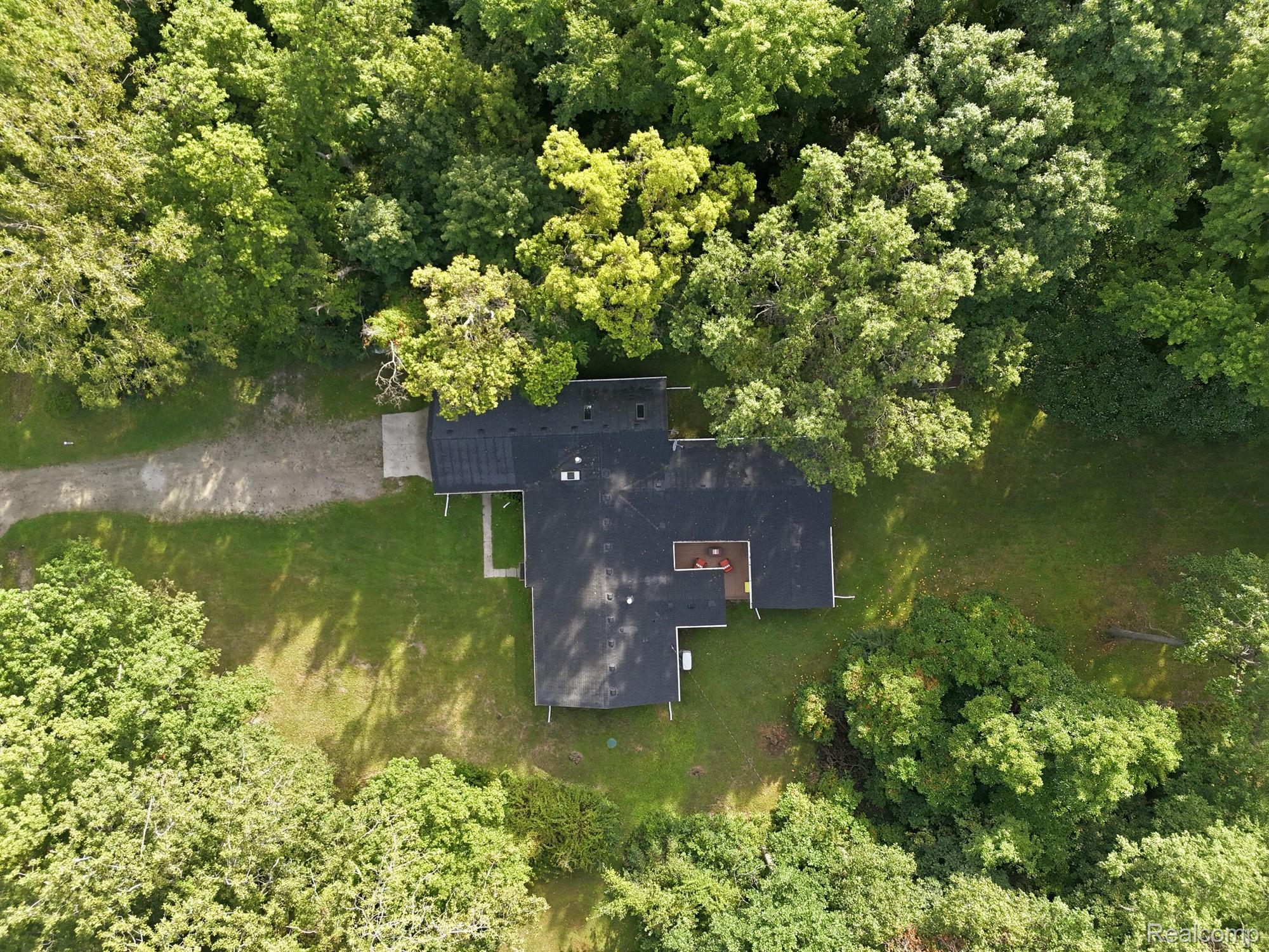 45223 Wear Road Belleville, MI 48111 - Photo 55 of 60 Expansive property featuring a black shingle roof, surrounded by mature trees, and a gravel driveway