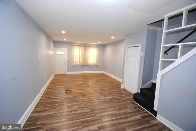 a view of an empty room with wooden floor and stairs
