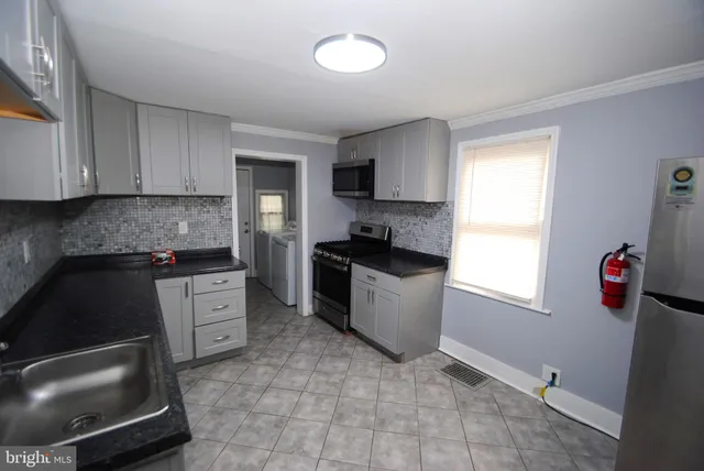 a kitchen with granite countertop a refrigerator stove and sink