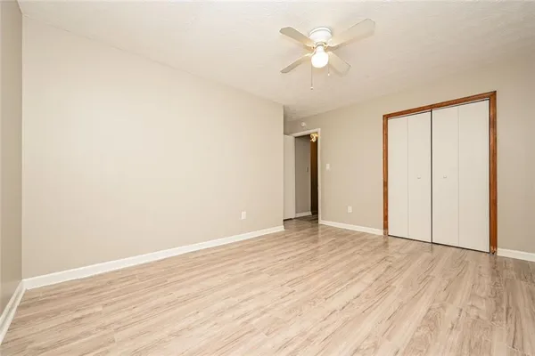 an empty room with wooden floor and a ceiling fan