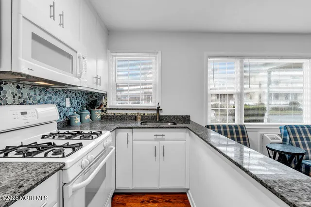 a kitchen with granite countertop a sink stove and cabinets