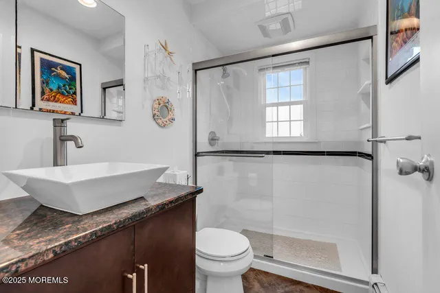 a bathroom with a granite countertop sink a toilet a mirror and a shower