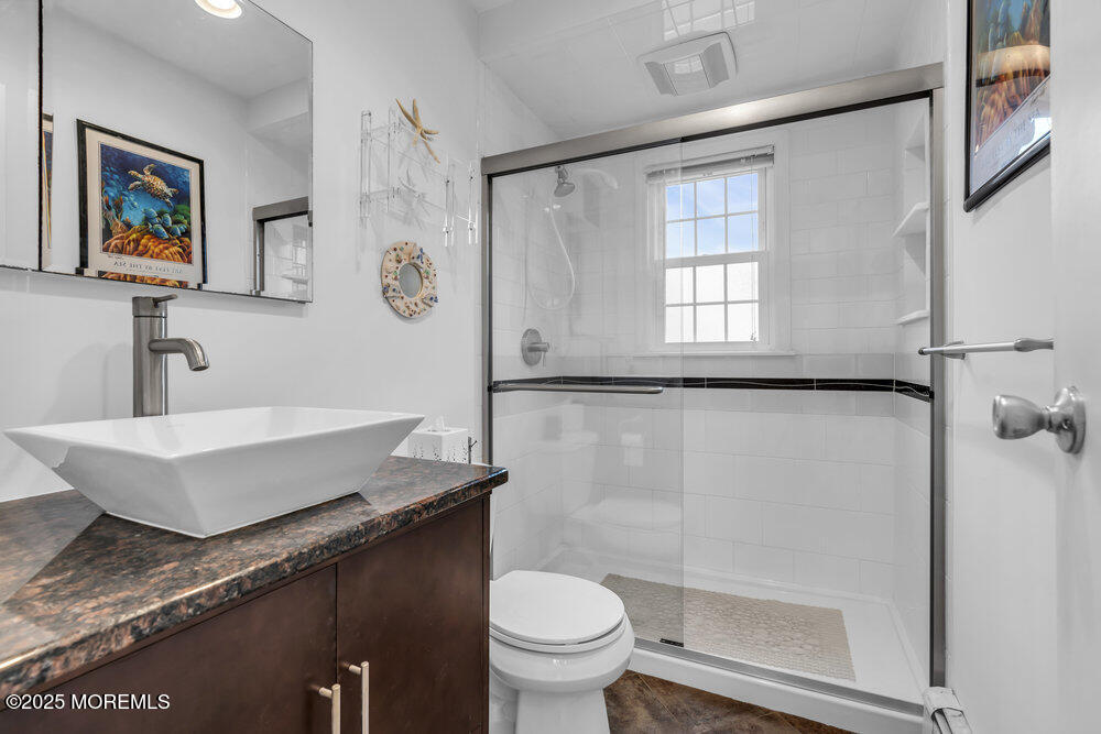 1304 Ocean Avenue, Unit 2A Belmar, NJ 07719 - Photo 16 of 25 a bathroom with a granite countertop sink a toilet a mirror and a shower