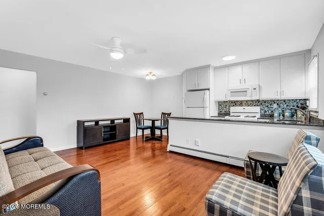 a kitchen with stainless steel appliances granite countertop a stove top oven a sink a dining table and chairs with wooden floor