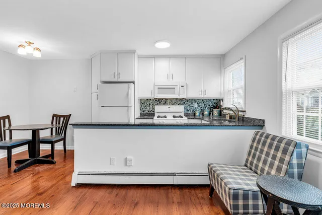 a kitchen with stainless steel appliances granite countertop a stove top oven a dining table and chairs with wooden floor