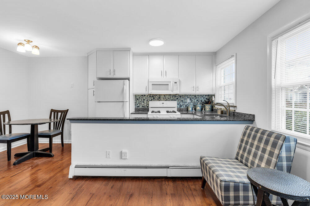 1304 Ocean Avenue, Unit 2A Belmar, NJ 07719 - Photo 6 of 25 a kitchen with stainless steel appliances granite countertop a stove top oven a dining table and chairs with wooden floor