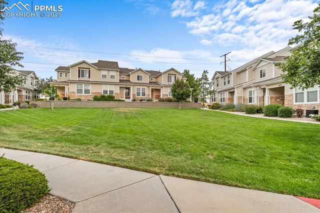 a view of a white house next to a yard with big trees