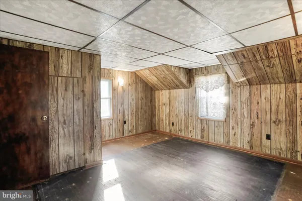 a view of an empty room with wooden walls and a window