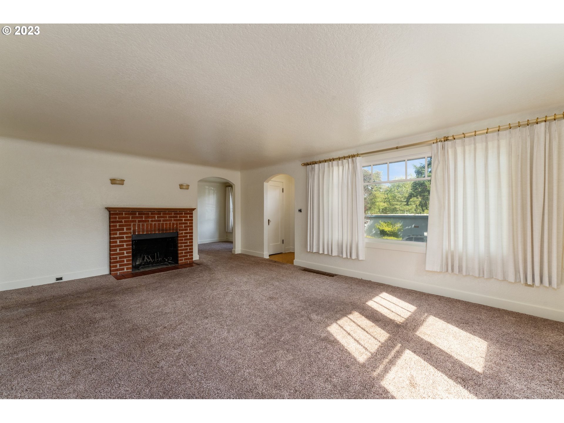 3148 Willamette Street Eugene, OR 97405 - Photo 2 of 31 a view of an empty room with a fireplace and a window