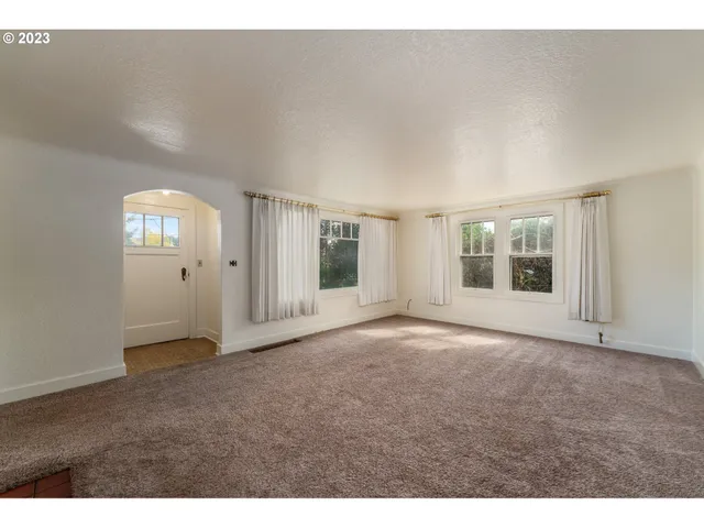 a view of an empty room with window and stairs