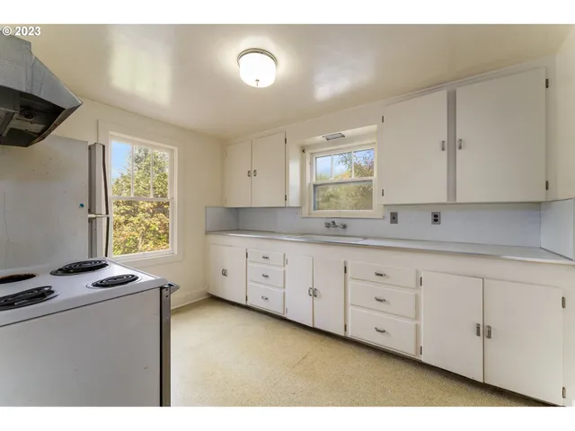 a kitchen with granite countertop white cabinets sink and a large window