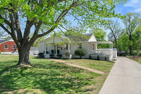 a view of a house with a big yard and large trees