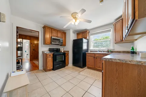 a kitchen with granite countertop a refrigerator a stove top oven a sink dishwasher and a dining table with wooden floor