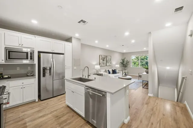 a kitchen with a sink a microwave a refrigerator and white cabinets