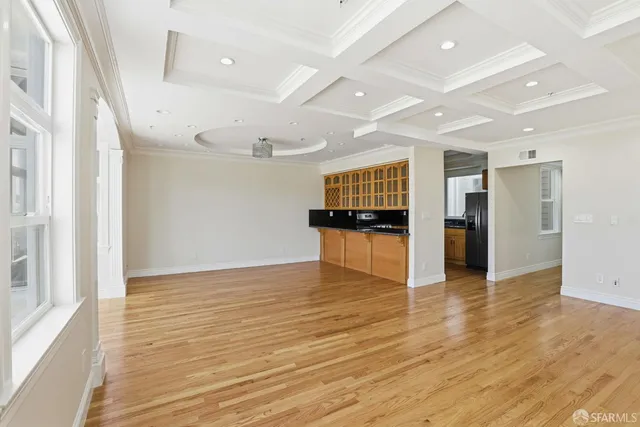 a view of an empty room with wooden floor fireplace and a window