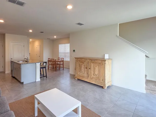 a living room with couches and kitchen view with wooden floor
