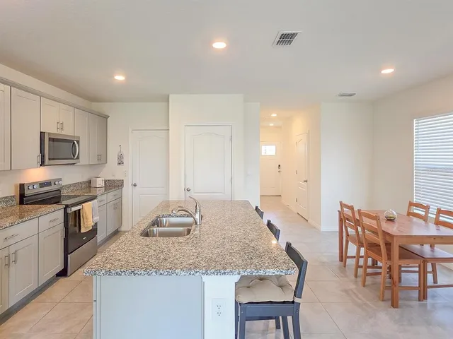 a large kitchen with granite countertop kitchen island a table and chairs