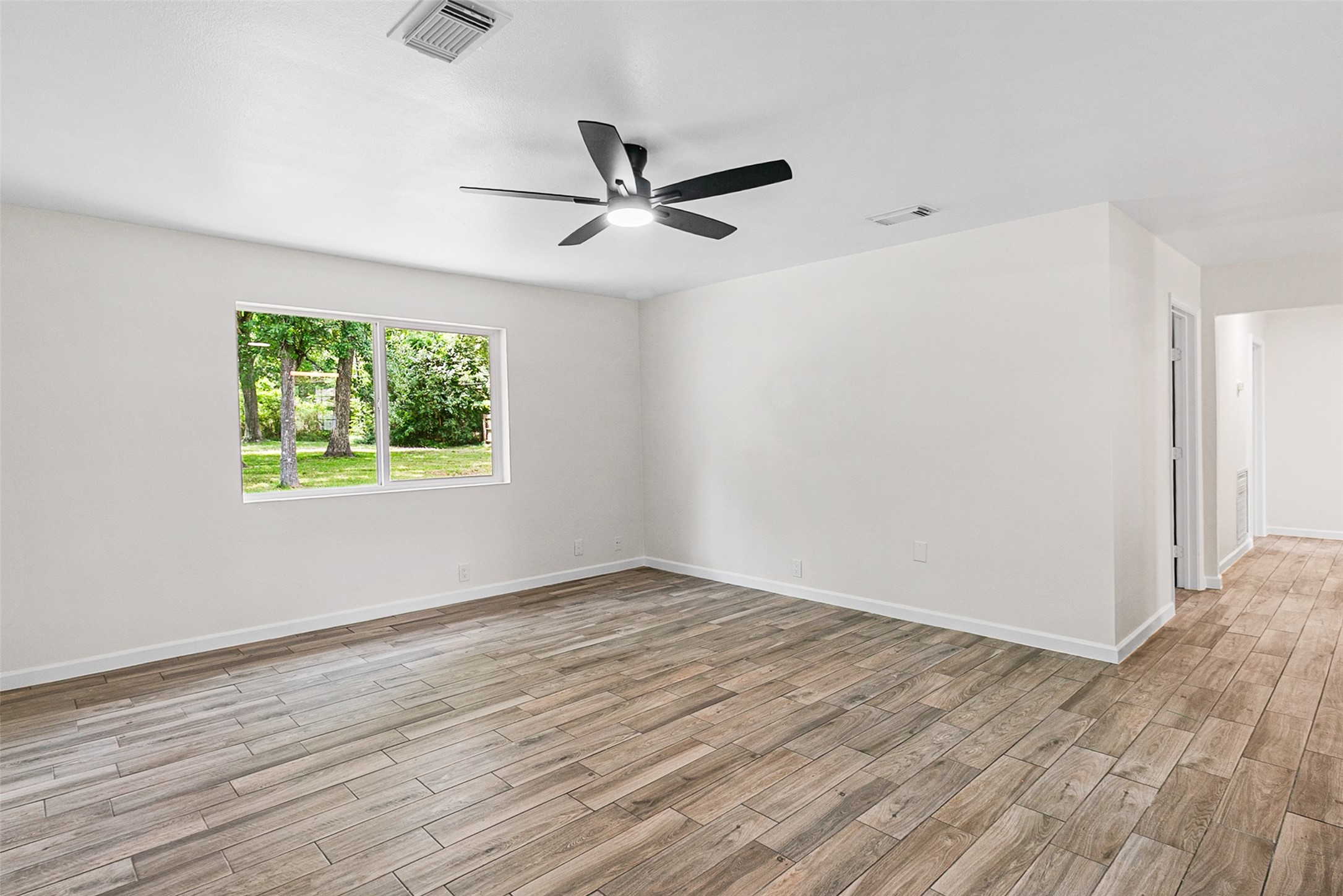 16715 Waycreek Road Houston, TX 77068 - Photo 3 of 41 an empty room with wooden floor ceiling fan and windows