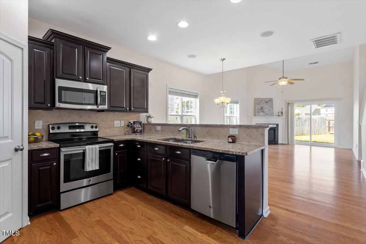 632 Hunters Ridge Drive Fuquay-Varina, NC 27526 - Photo 11 of 28 a kitchen with stainless steel appliances granite countertop wooden cabinets a stove top oven a sink and dishwasher