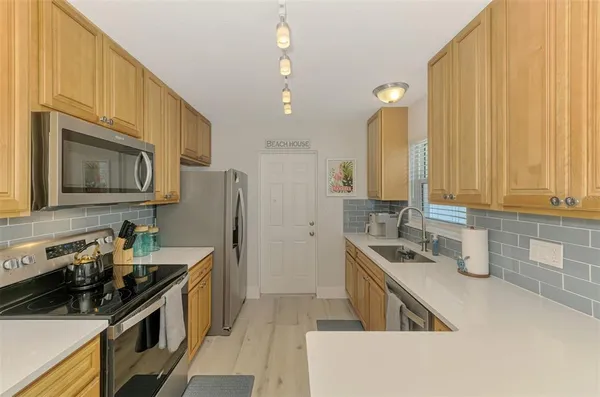a kitchen with stainless steel appliances kitchen island granite countertop a refrigerator a stove a sink dishwasher and white cabinets with wooden floor