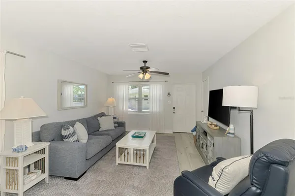 a living room with furniture a ceiling fan a lamp and a window