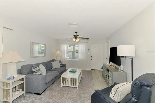 a living room with furniture a ceiling fan a lamp and a window