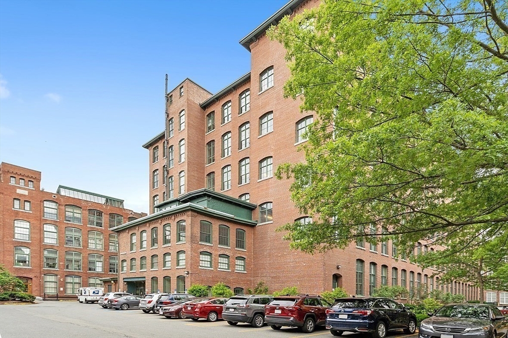 200 Market Street, Unit 117 Lowell, MA 01852 - Photo 28 of 37 a front view of a building with lot of cars and trees
