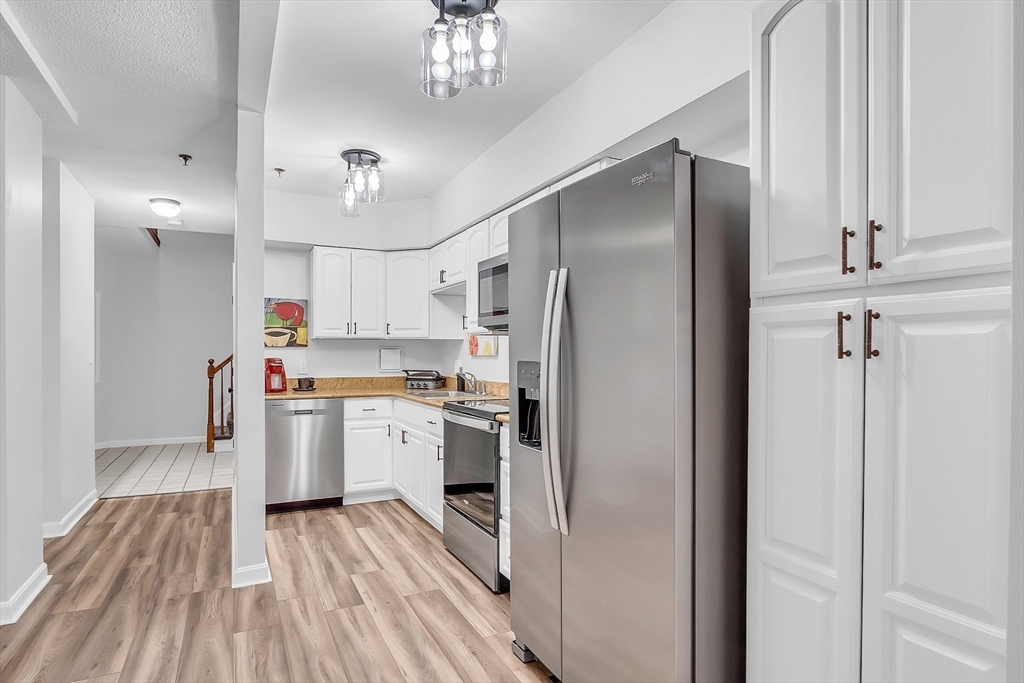 200 Market Street, Unit 117 Lowell, MA 01852 - Photo 3 of 37 a kitchen with a refrigerator a sink and dishwasher a oven with wooden floor