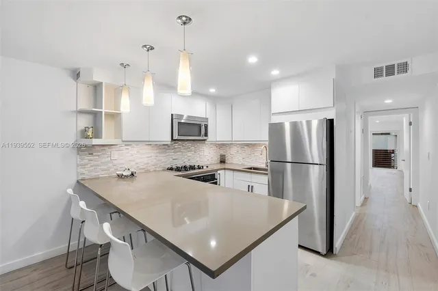 a kitchen with stainless steel appliances granite countertop a refrigerator a stove a sink a dining table and chairs