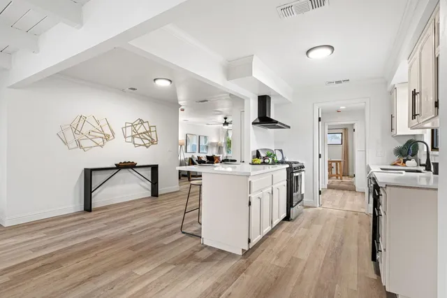 a large kitchen with a center island wooden floor stainless steel appliances and living room view