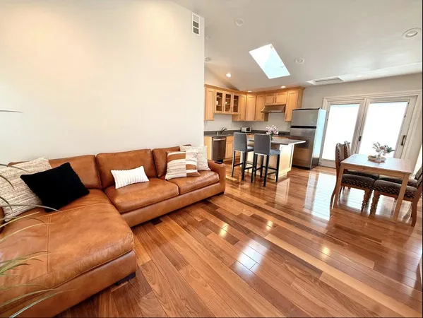 a living room with furniture and a dining table with wooden floor