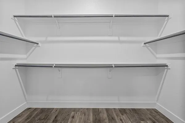 an empty room with wooden floor closet and windows