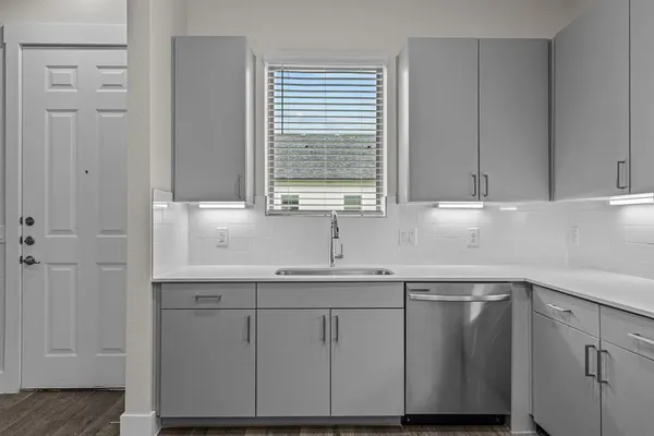 a kitchen with white cabinets and a window