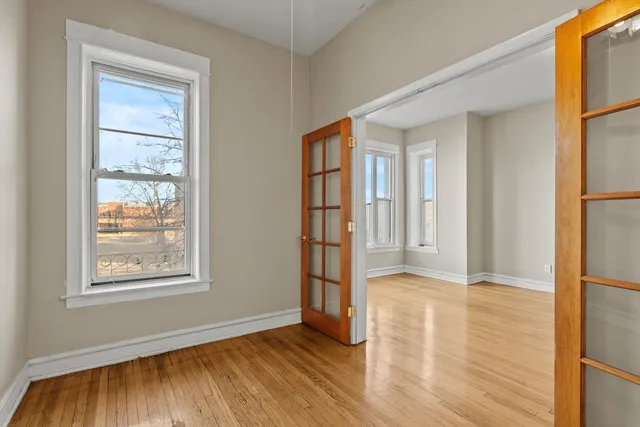 a view of an empty room with window and wooden floor