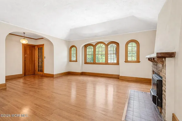 a view of empty room with wooden floor and a fireplace
